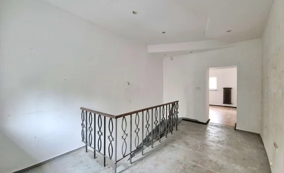 Antresola lokalu usługowego z metalową balustradą, oknem oraz schodami prowadzącymi na niższą kondygnację.