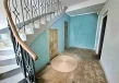 Klatka schodowa w lokalu usługowym z metalową balustradą, schodami prowadzącymi na antresolę oraz wejściami do pomieszczeń pod schodami.