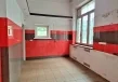 Pomieszczenie lokalu usługowego z czerwono-grafitową okładziną ścienną, dużymi oknami oraz przygotowaną instalacją pod zabudowę.